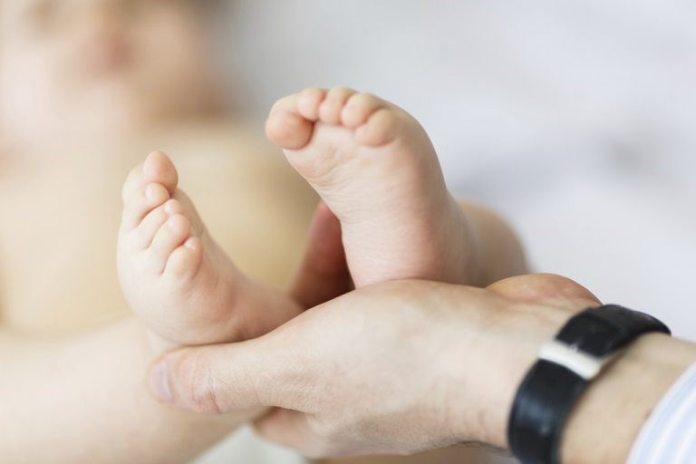 Baby foot in father's hand on the white background