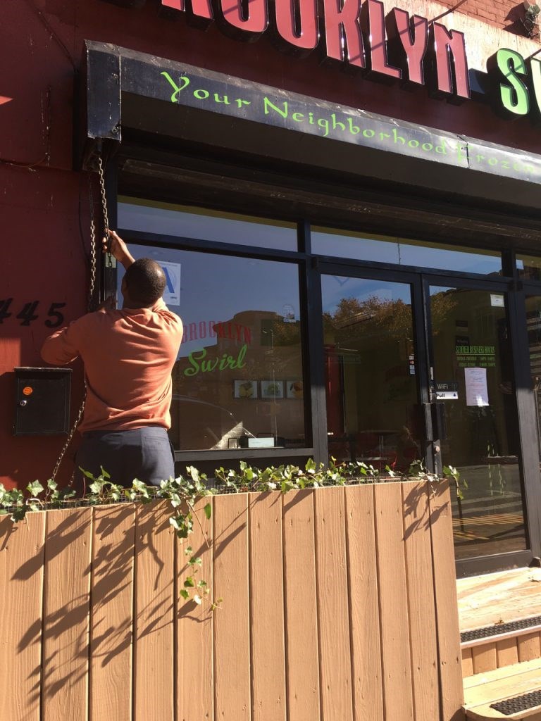 Jean Alerte, owner of Brooklyn Swirl, pulls down the store's gate for the final time this year.