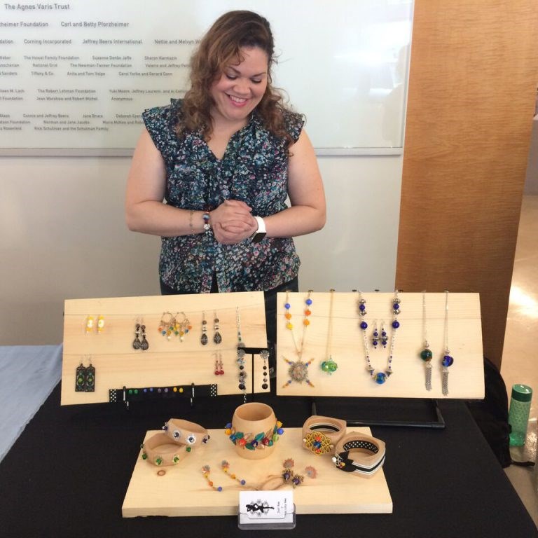 Bead Project alum Lilly Burgos showing off her jewelry line at the Bead Project Graduation Trunk Show in the Gallery at UrbanGlass. Photo credit: Amy Lemaire