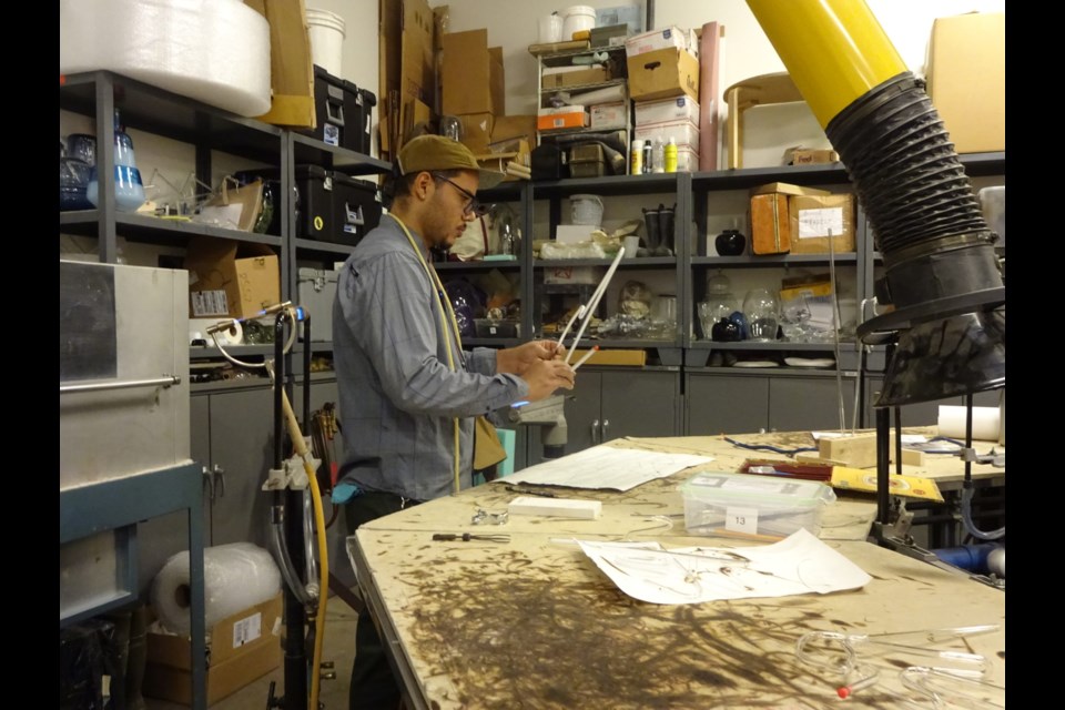 Artist works with glass tube that he will eventually fill with gas.