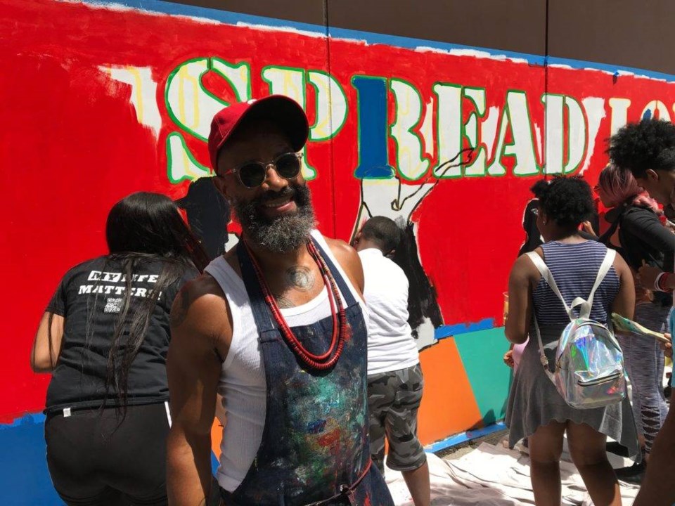 Patrick Dougher stands in front of the "Spread Love" mural