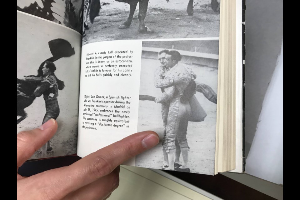 Rachel Miller points to a photo of Sidney embracing a fellow bullfighter on the day he became certified in Madrid. Photo credit: C. Innis for BK Reader