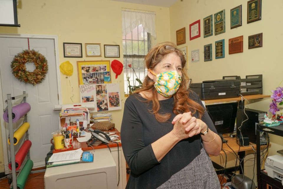 Maria Collier, director of the Cypress Hills Child Care Corporation, stands in front of her desk. Photo by Russell Frederick.