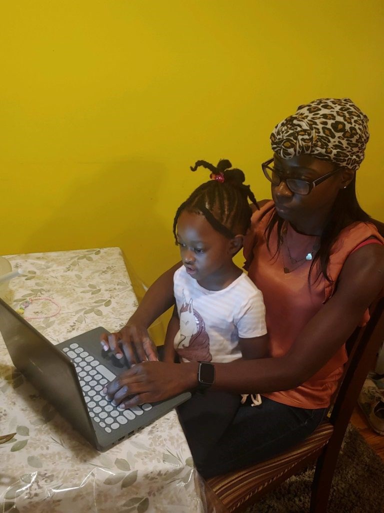 Mother helps her toddle with virtual learning classroom.