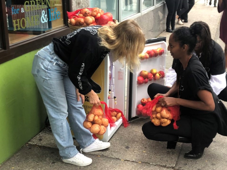 Asmeret Berhe-Lumax adding fresh produce to her community fridge in Clinton Hill, at 432 Myrtle Ave. Photo: Miranda Levingston for the BK Reader.