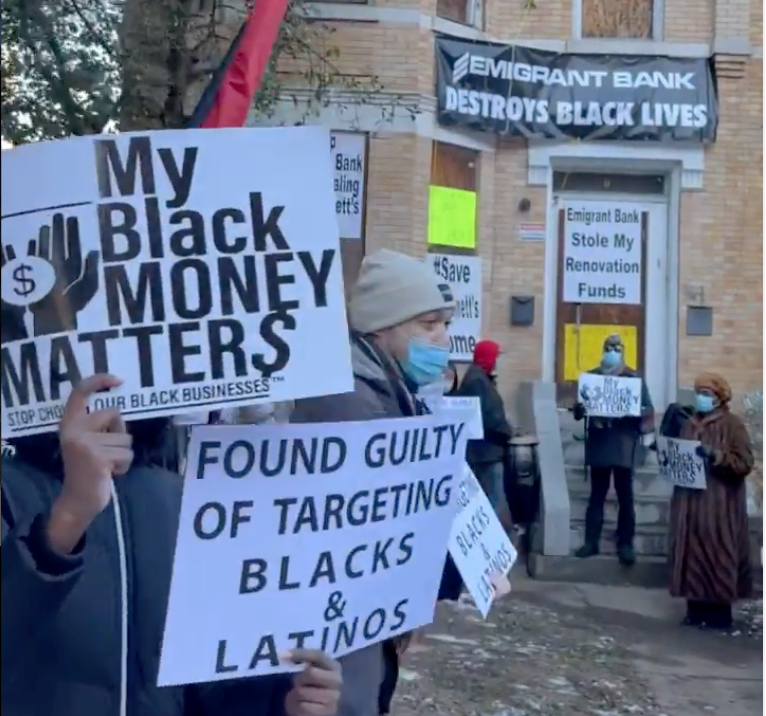 Protesters hold up signs critical of Emigrant Bank.