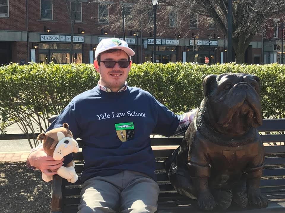 Edward with Handsome Dan (Yale University mascot) statue and plushie and wearing Yale Law School apparel when he committed in March 2021.