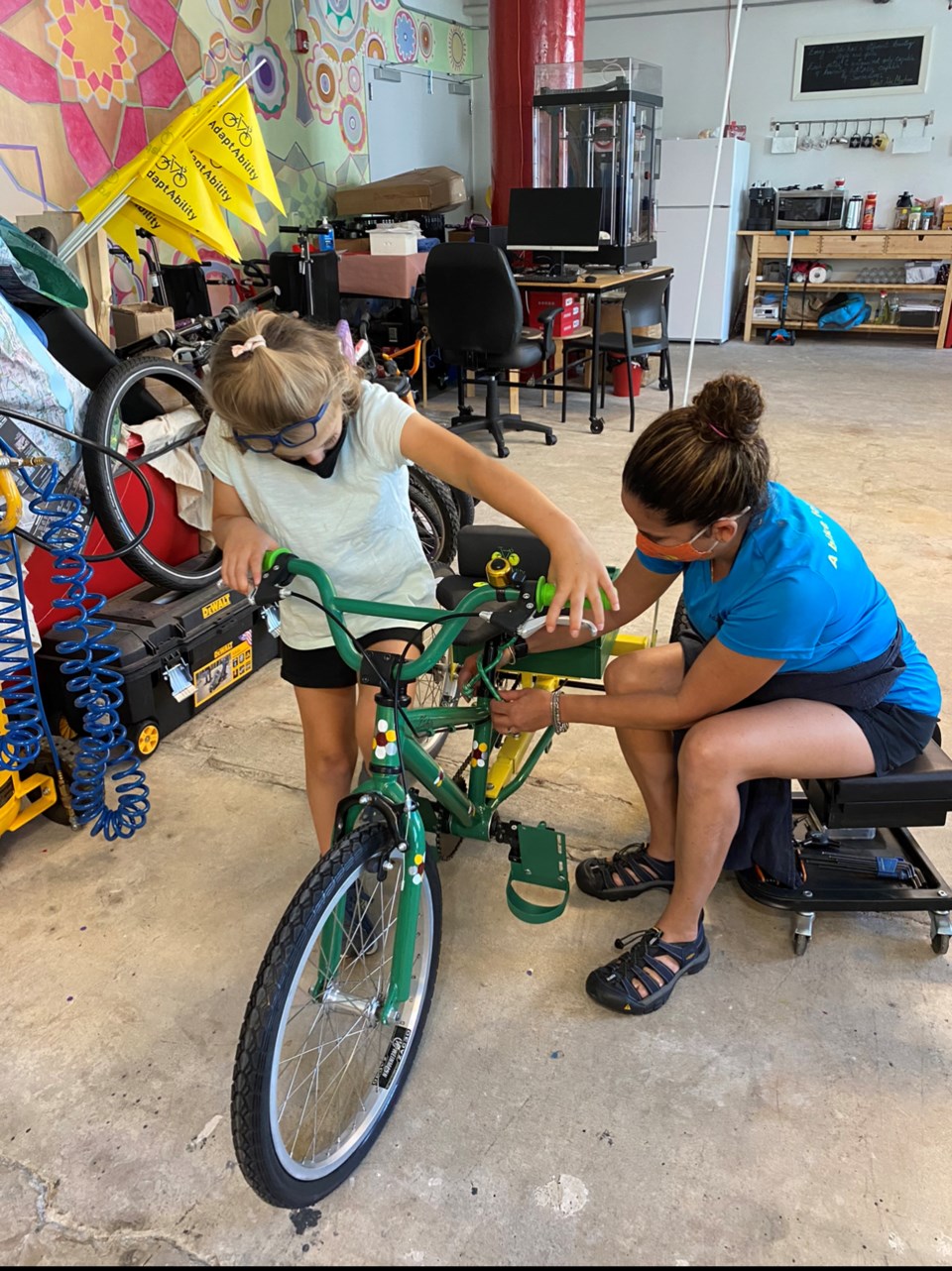 Child being helped with getting on adaptive bike.