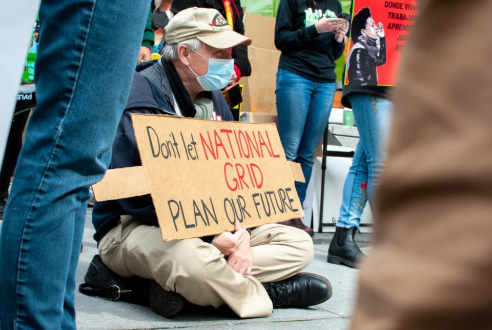 Man sits with sign at climate rally