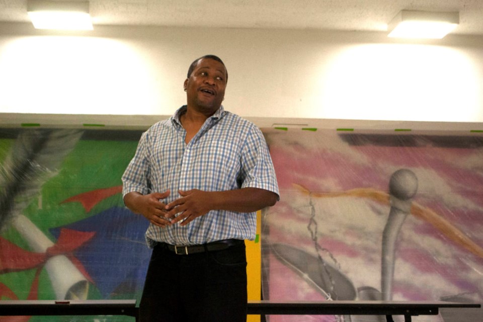 Renard Kelley stands in front of two murals