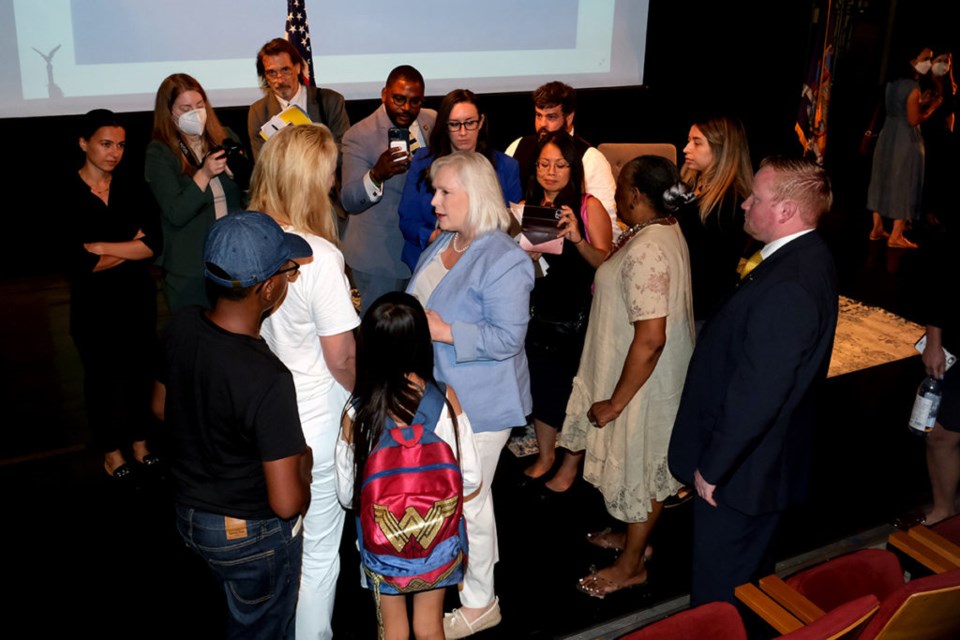 A crowd gathers around Sen. Kirsten Gillibrand on the stage floor, as she talks with a constituent in the center.