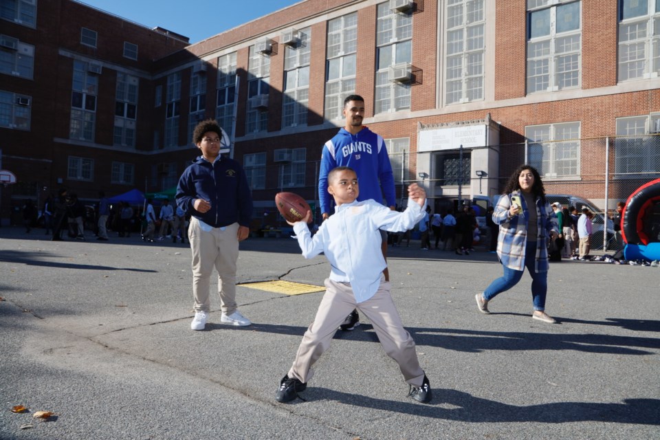 NY Giants player Elerson Smith watches student go for the pass  
Photo: Courtesy of Harol Baez. 