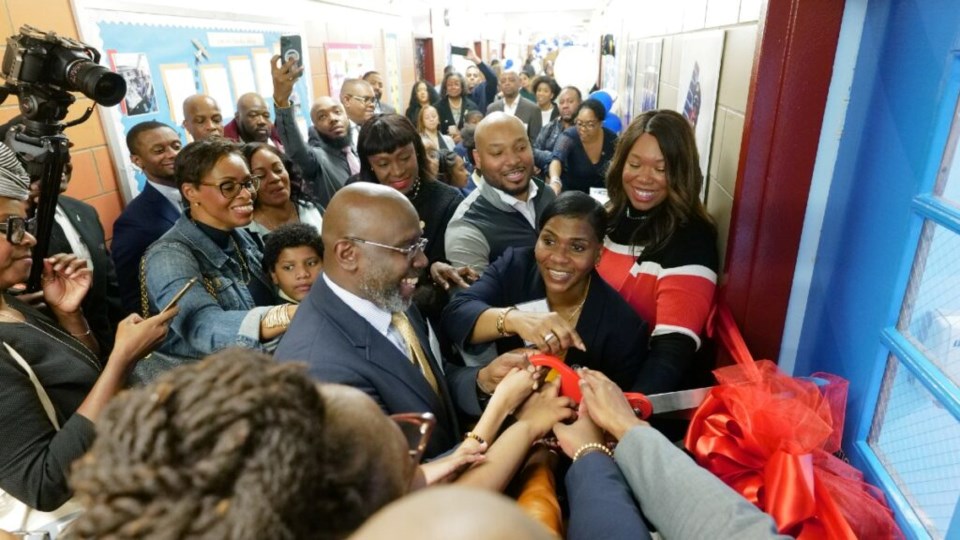 Principal Lena Gates is joined by elected officials, civic leaders, American Airlines, students, faculty staff and family members in officially cutting the ribbon to open the door for the Bed-Stuy aviation school center. Photo: Supplied/PS 5.