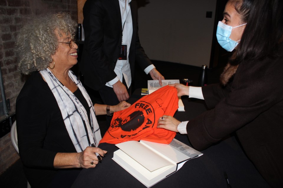Davis signs a 'free Angela' shirt, which references the year she spent in prison. Photo: Miranda Levingston for BK Reader.