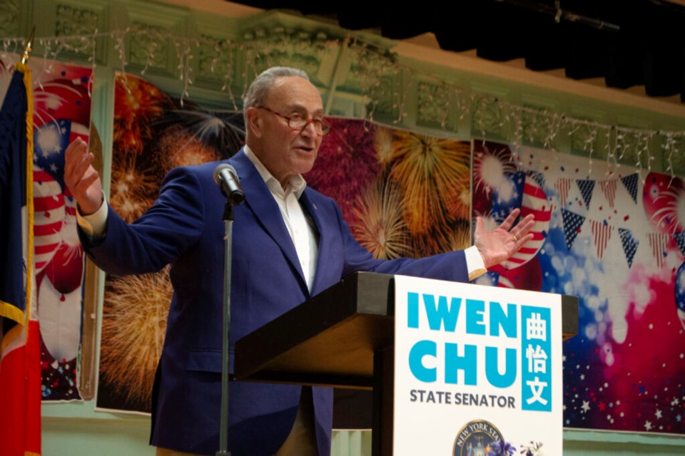Chuck Schumer speaks in front of a podium that reads "Iwen Chu. State Senator."