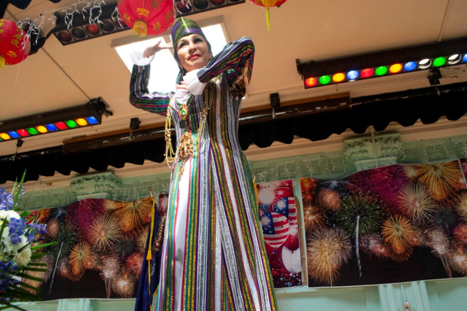 A woman in colorful attire performs an Uzbek tanovar dance on stage atPublic School 176 in Dyker Heights