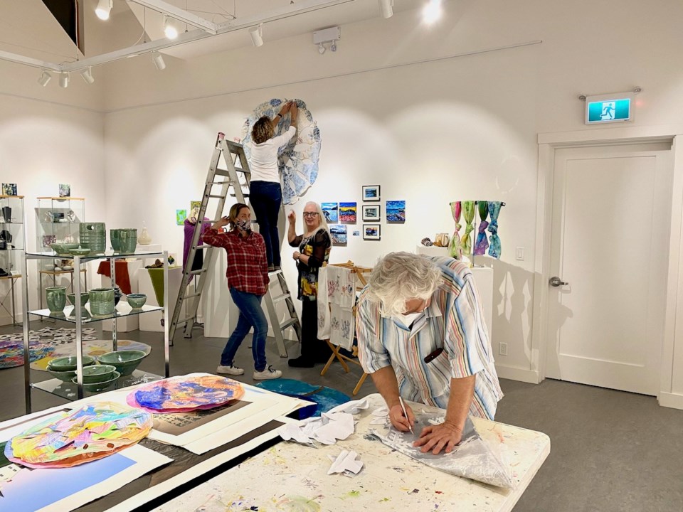 Inside the Hearth gallery, Michael cutting snowflakes, Jami affixing a snowflake on the wall