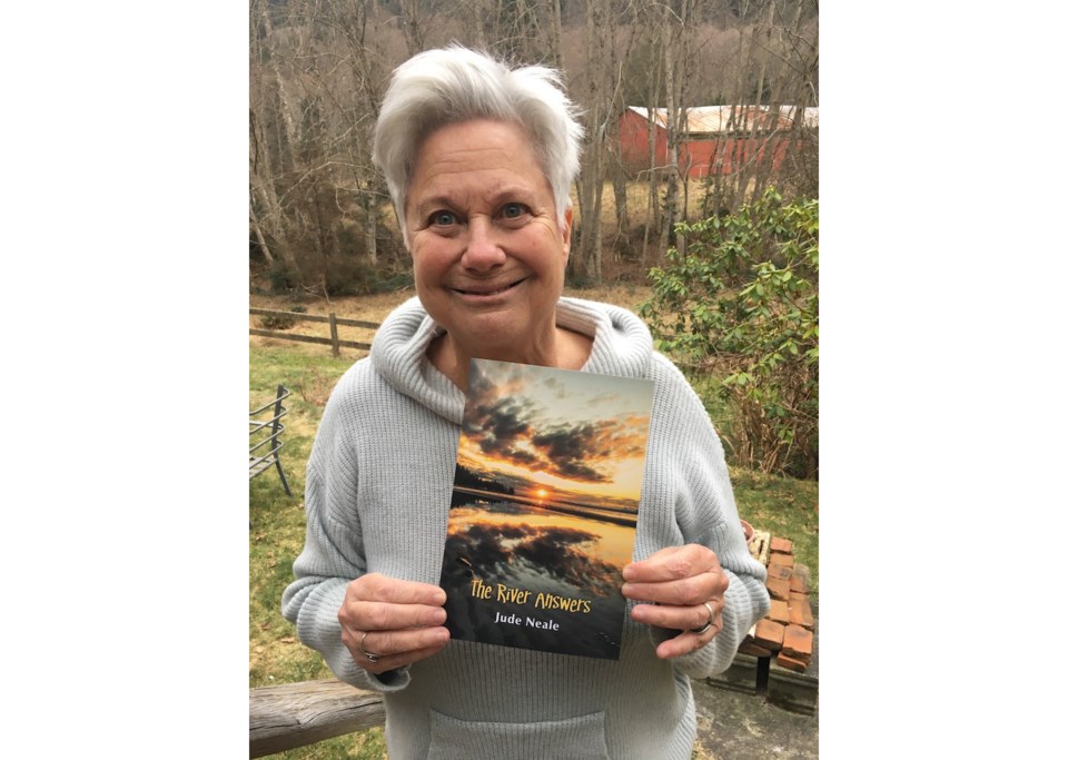 Jude Neale holding her ninth book of poetry