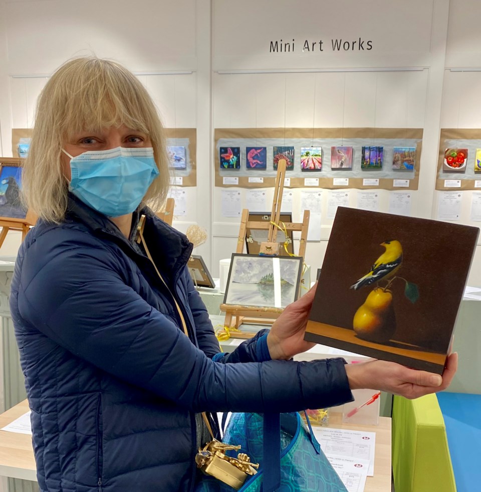 Woman holding a painting of a bird sitting on a pear