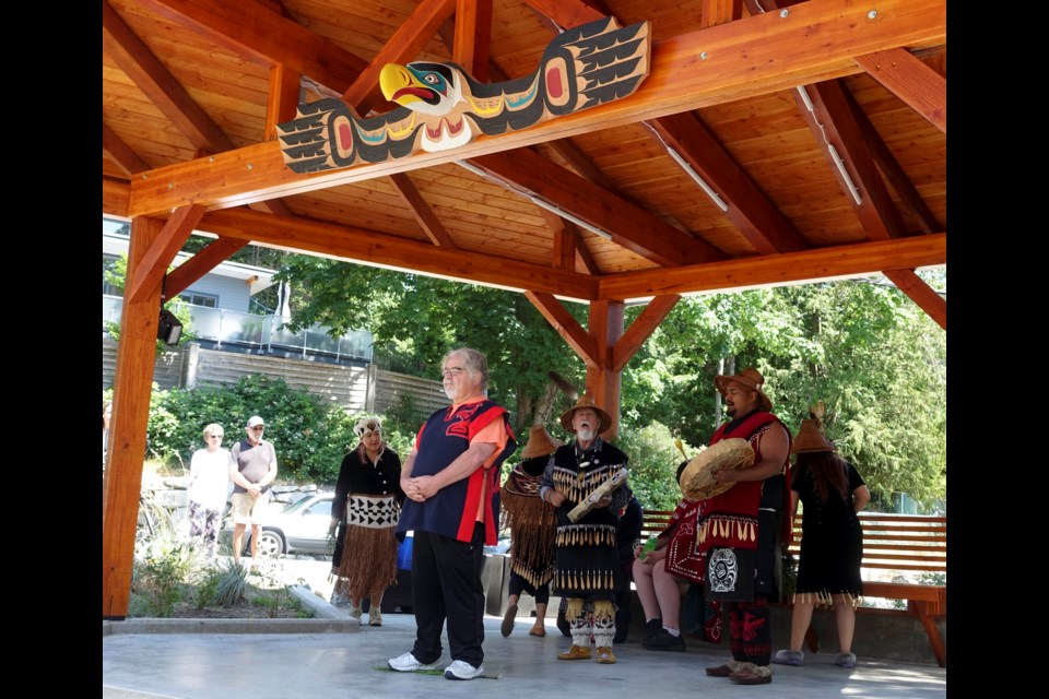 Simon Daniel James stands underneath the carving he created for the Cultural Corner space in the Cove. James was joined on June 25 by Bob Baker and the Squamish Eagle Song Dancers for an unveiling and blessing ceremony for himself and his work.
