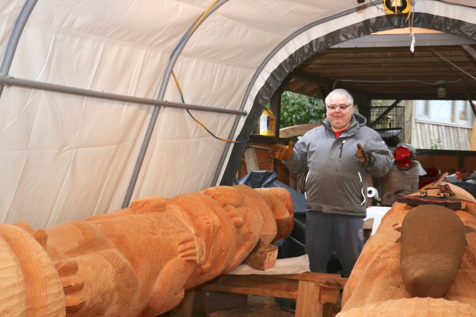 James standing with two totem poles in the workshop Feb. 2021