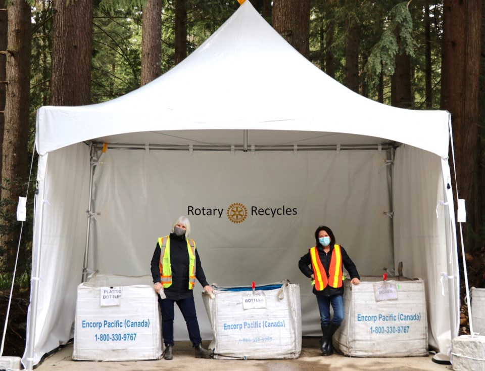 Louise McIntosh and Jan Seaman standing in a tent with giant bins for refundables