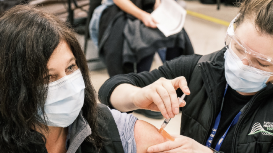 Stock image of a man injecting a woman with a COVID-19 vaccine