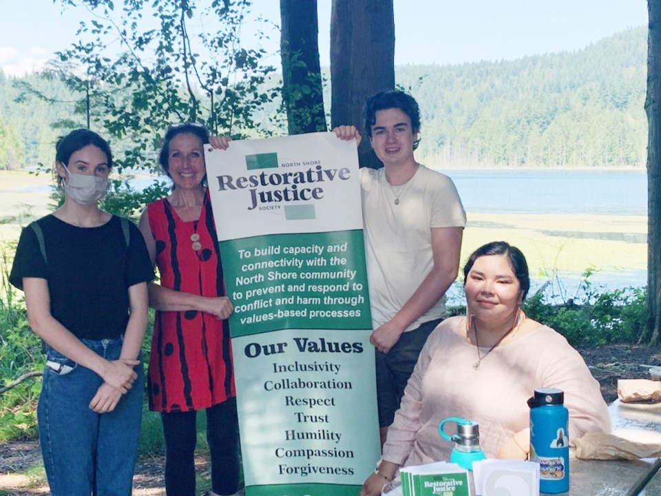 Four people standing with a banner like thing at Killarney Lake