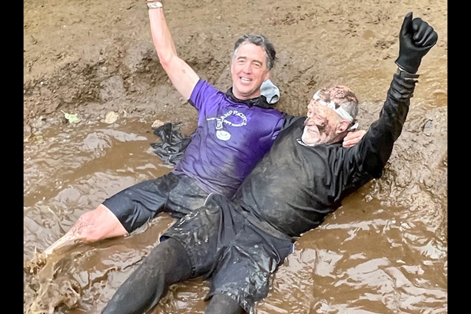 Current head of school Scott Herrington and school founder Ted Spear take a dip in the mud bath.