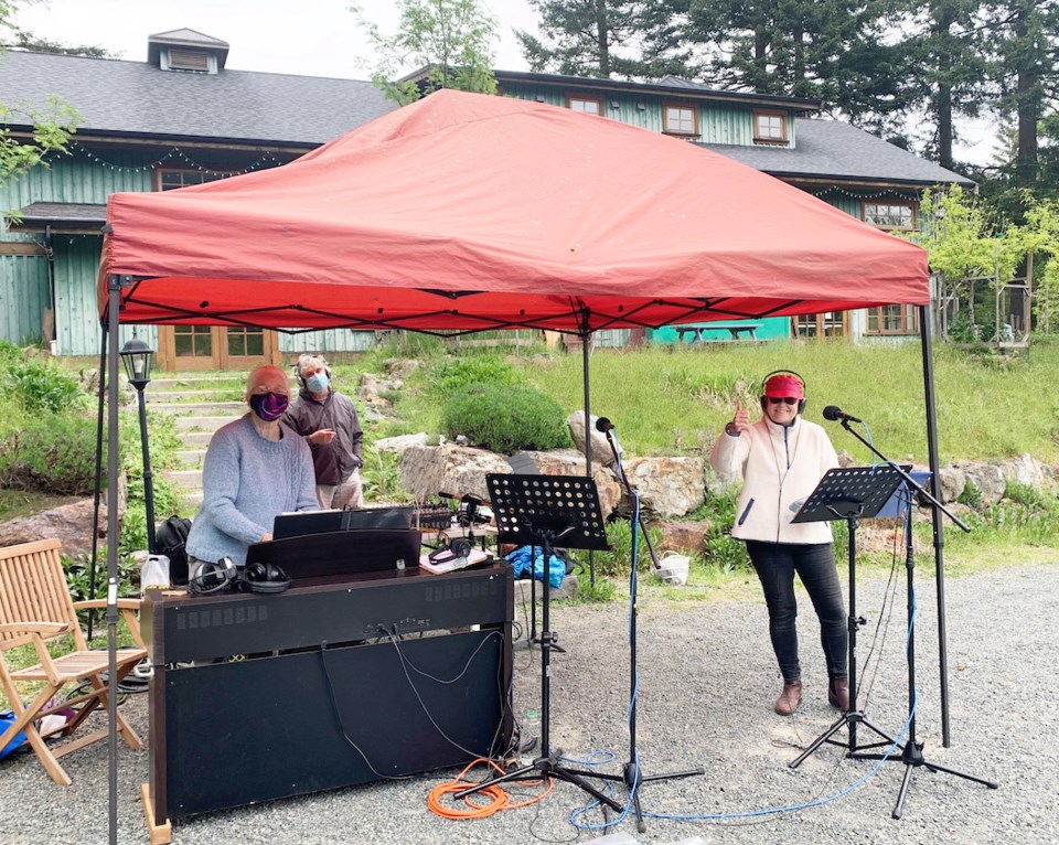 Three people standing under a tent with music and sound equipment