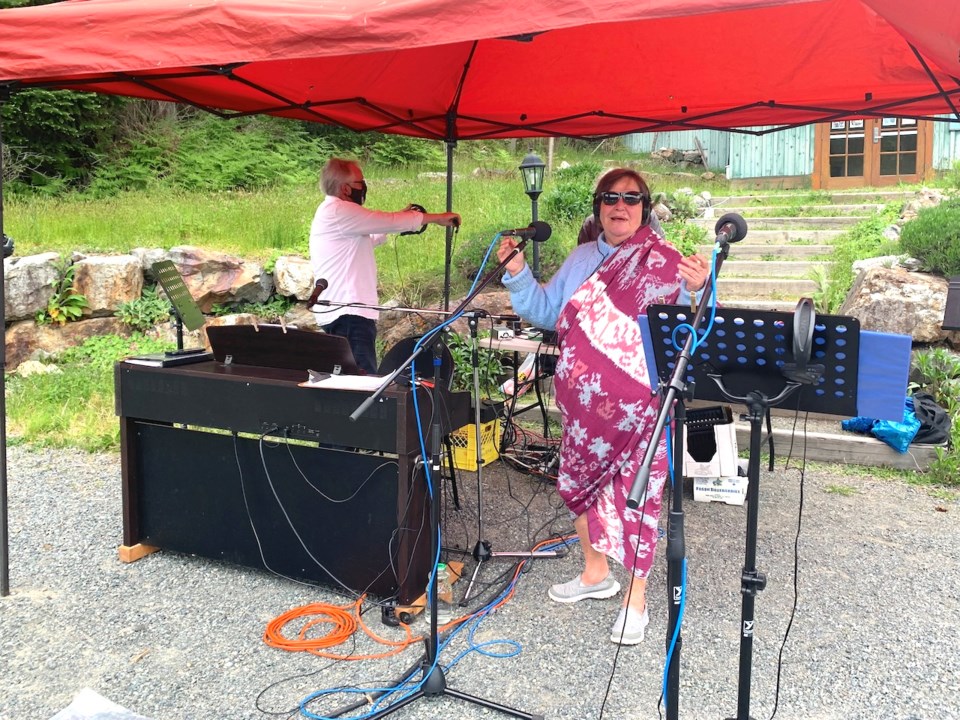 Two people standing under a tent with music and sound equipment
