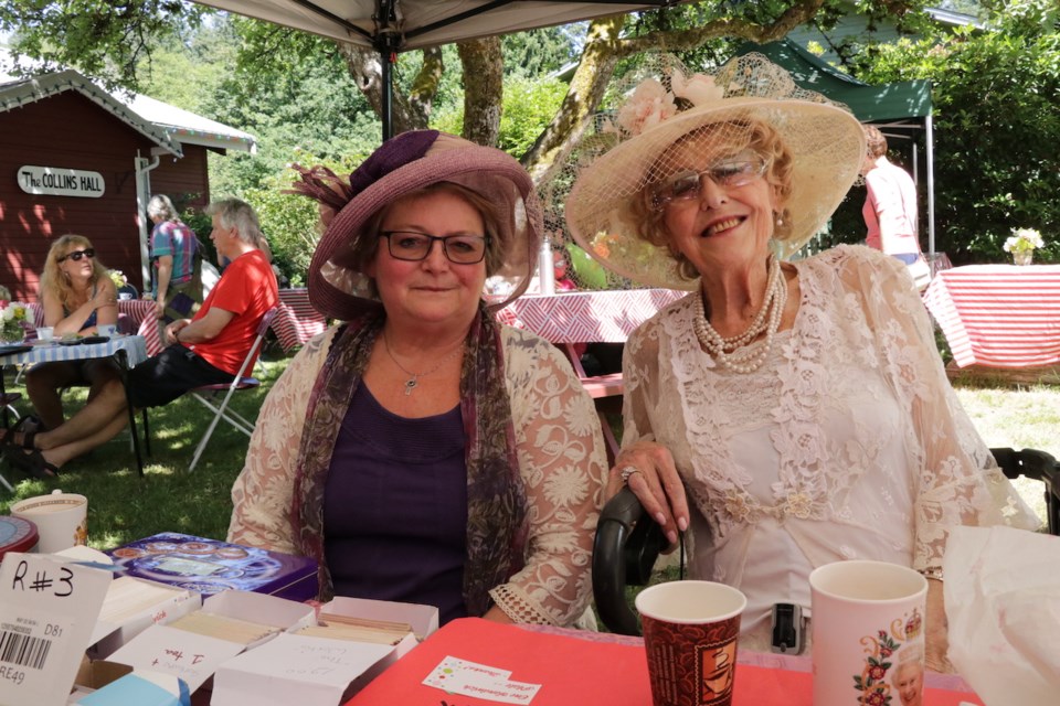 Two women in fancy tea outfits outside