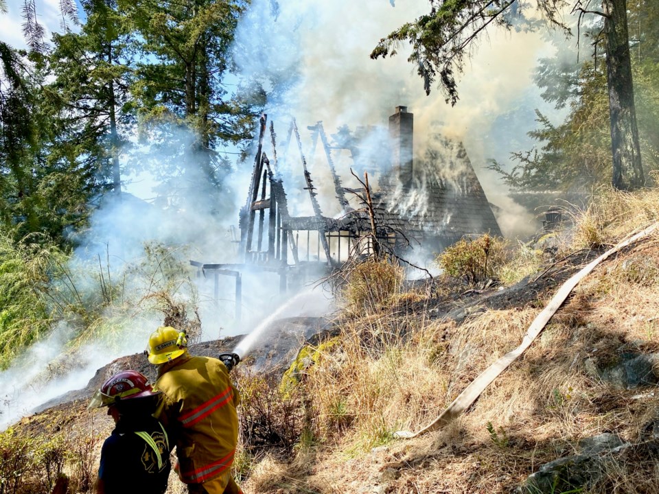 Two firefighters hosing down the smoking skeleton of a building