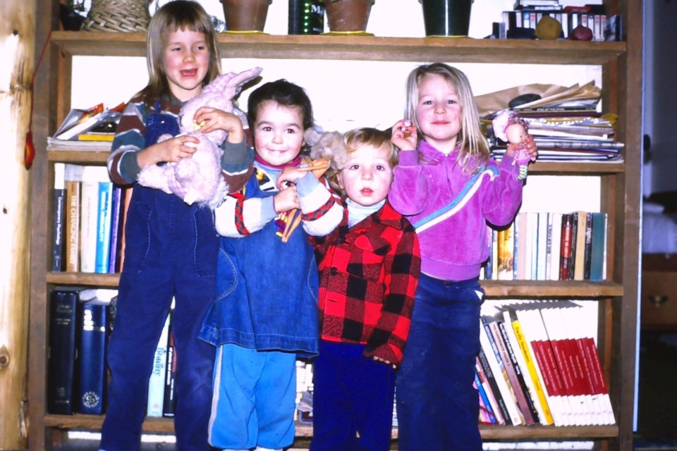 Four kids lined up in front of a bookshelf 