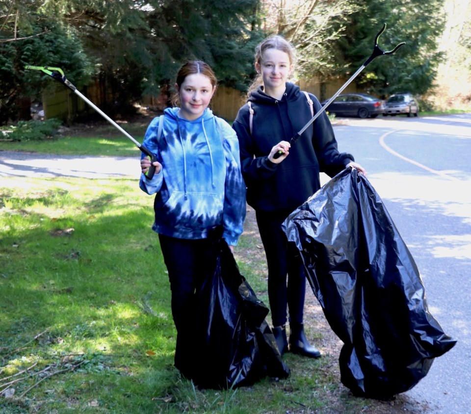 Ela and Hadley hold up their trash pickers