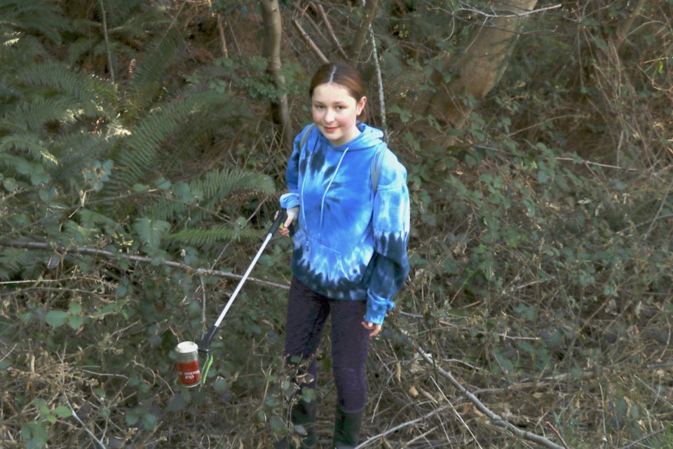 Ela in a ditch holding a beer can with a trash picker