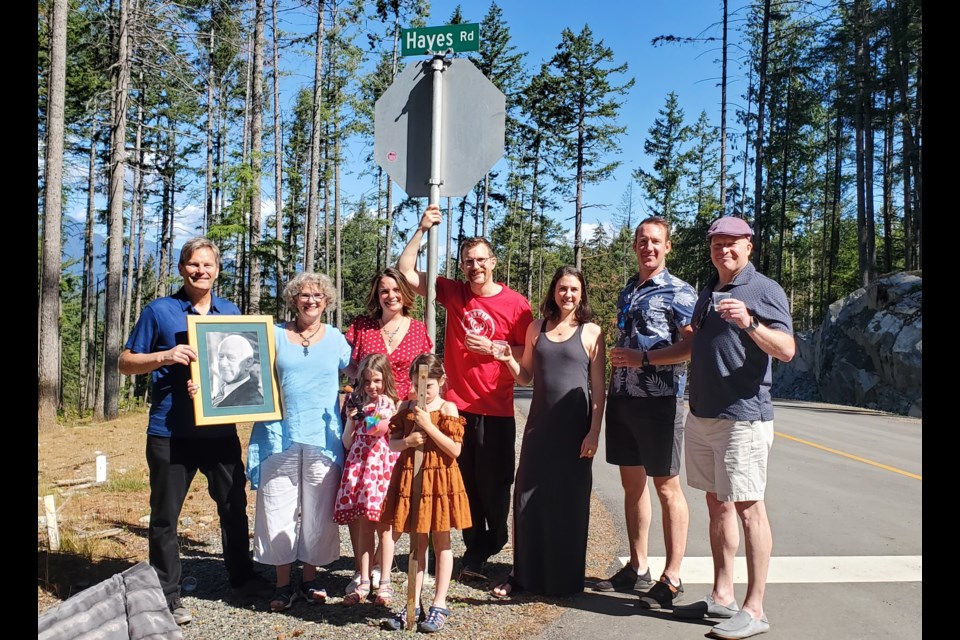 Arbutus Ridge developers Allard Ockeloen (far left) and David Beckow (far right) - who decided on the name - joined the Hayes family (L-R) Joan Hayes (with photo of her husband Piers), Seonaid Hayes, William Hayes, Sarah-Jane Curry, Gord Curry, (front) Iona Hayes, and Madeleine Curry for the unveiling of the newly named Hayes Road earlier this month. Miles Hayes and Elijah Curry (not pictured) are also proud of the dedication to Piers.