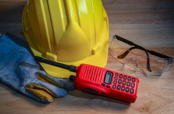A hand-held radio with a hard hat and work glasses