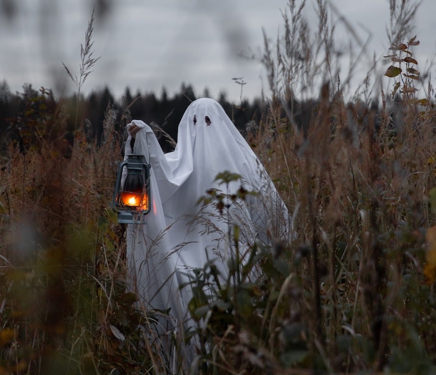 person in ghost costume holding lantern