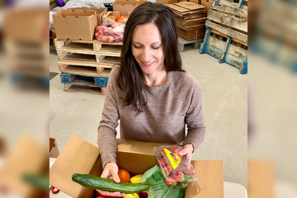 Eat Impact Founder Anna Stegink packs one of the produce boxes offered by the service.
