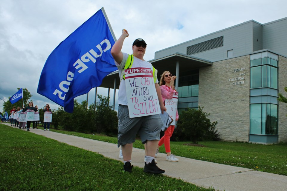 Library staff and CUPE members walk the picket, waving flags and holding signs in support of staff outside the Bradford West Gwillimbury Public Library on Friday, July 21, 2023.