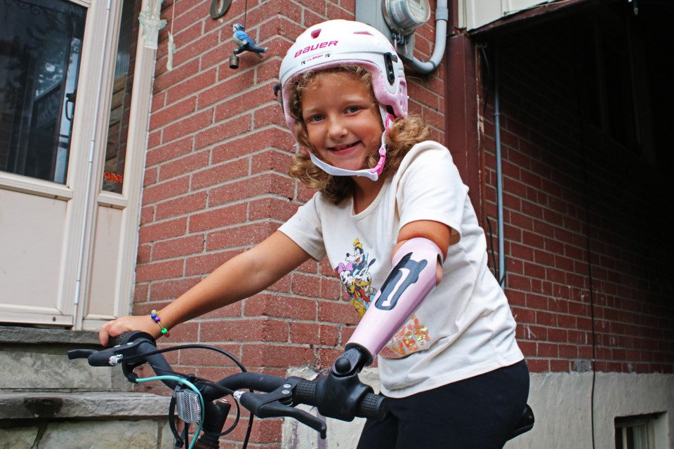 Michaela Blakslee of Holland Landing shows how an attachment for one of her prosthetic arms allows her to hold onto the handlebars of a bicycle, at her grandparents’ home in Newmarket on Tuesday, Sept. 12, 2023.