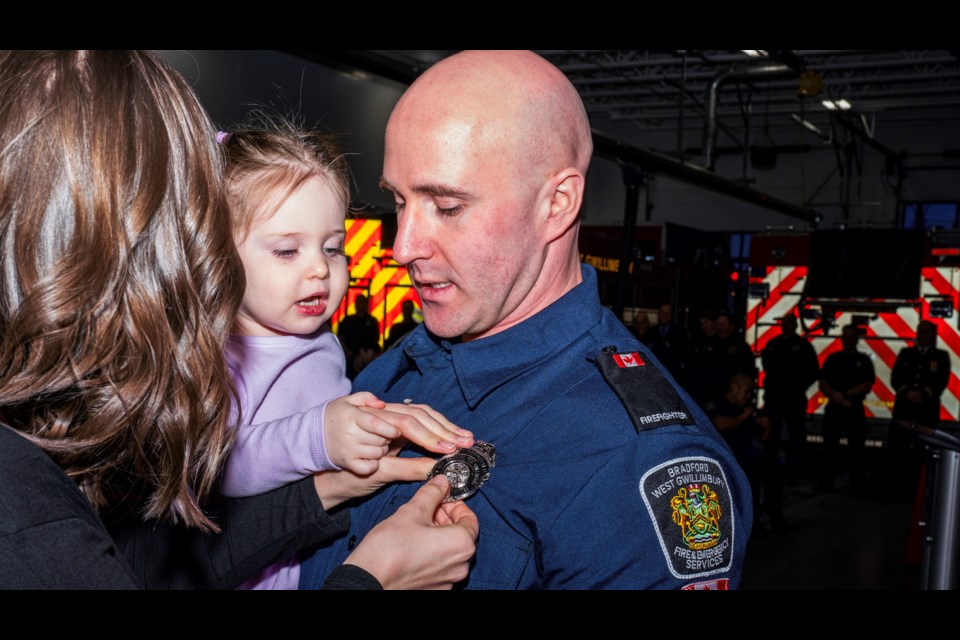 Firefighter Travis Steeves receives his new badge with the help of his daughter and wife.