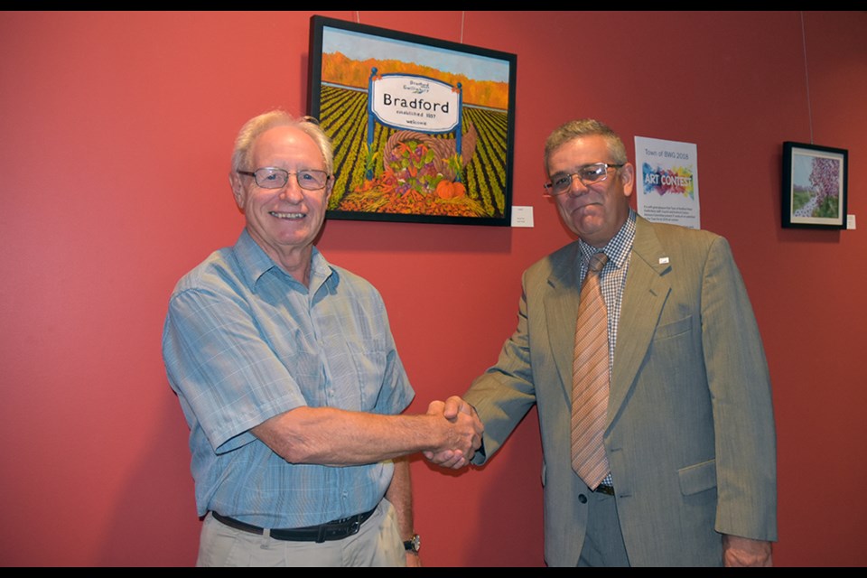 Deputy Mayor James Leduc, right, congratulates winner Jim Woods, with his painting ‘Harvest Time.’ Miriam King/BradfordToday
