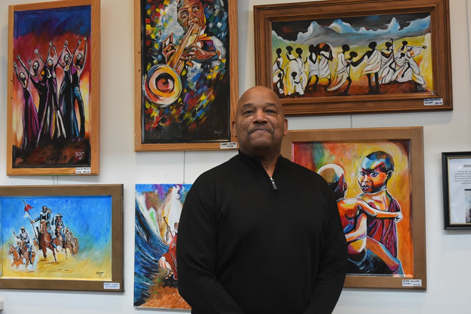 Artist Stanley Thomas, with some of his vibrant, colourful artwork, at the BWG Public Library. Miriam King/Bradford Today