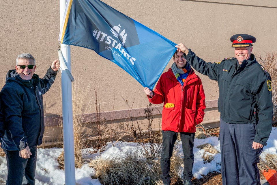 Bradford Mayor James Leduc, BWG Public Library Manager of Cultural Services, David di Giovanni and South Simcoe Police Service Chief John Van Dyke raise the #ITSTARTS flag. Paul Novosad for Bradford Today.