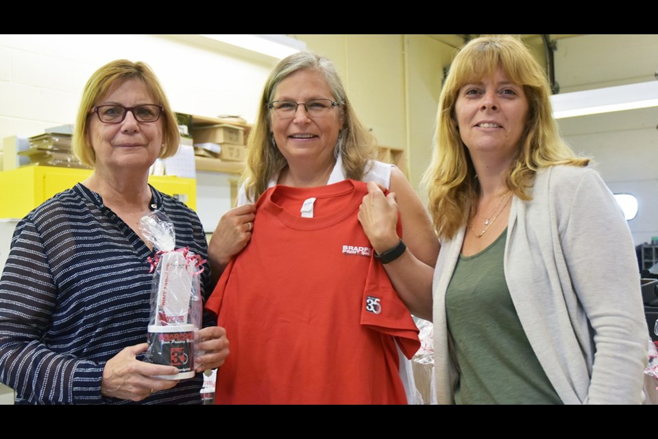 Mikki Nanowski, from left, and Bradford Print Shoppe staff Cynthia Dixon and Annette Davey, with giveaways for the business's 35th anniversary celebration. Miriam King/Bradford Today