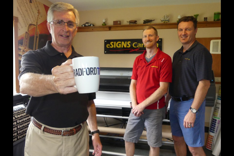 eSigns Canada President Gary Brickell, from left, production manager Jesse Brickell and art director Chris Muncey in front of a digital printer that can print 89 centimetres of material per second. Jenni Dunning/BradfordToday