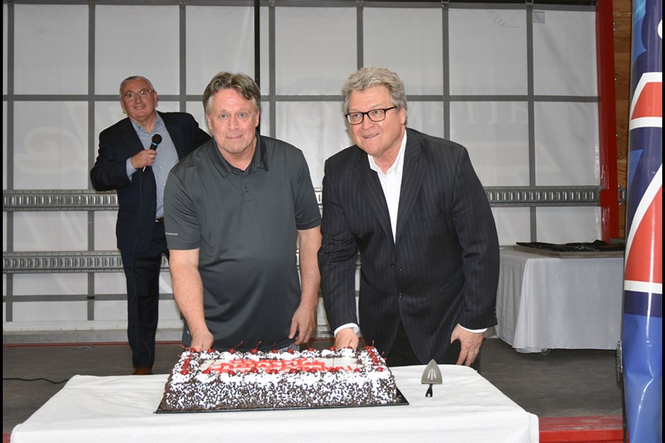 Ken Simpson, right, and brother Stephen cut their retirement cake at Array in Bradford, May 17. Miriam King/Bradford Today