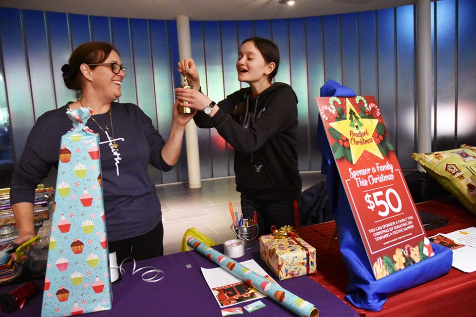 Emily, left, gets help from mom at the present-wrapping venture, raising money for A Bradford Christmas and 200 festive Christmas hampers. Miriam King/Bradford Today